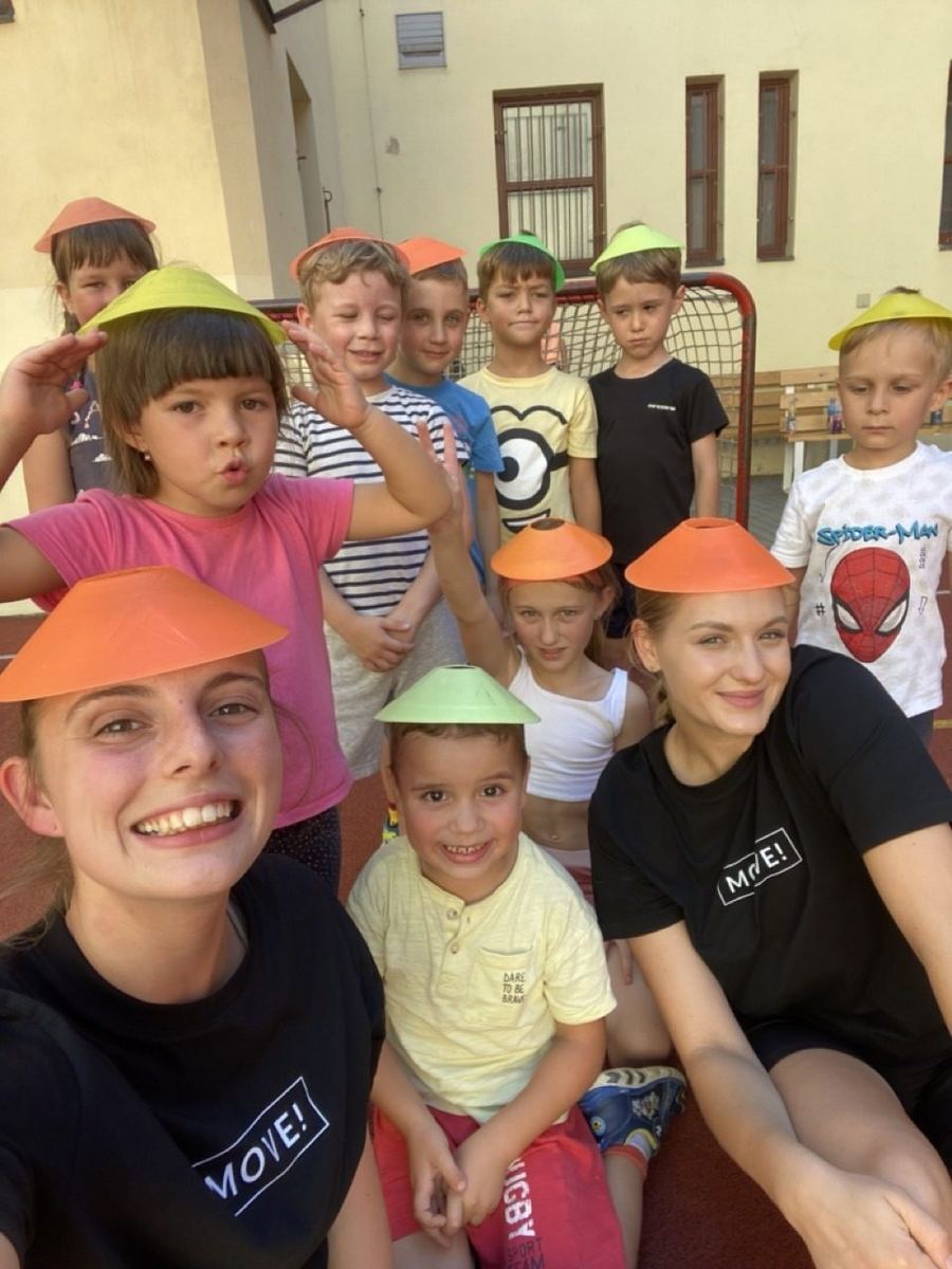 Trenérky MOVE! s dětmi na kempu, děti mají na hlavách kloboučky z kuželů